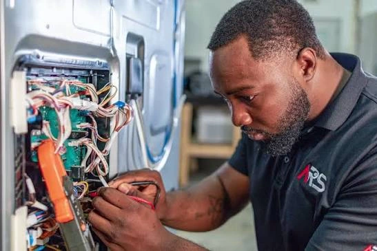 Technician inspecting exposed appliance wiring and electrical components