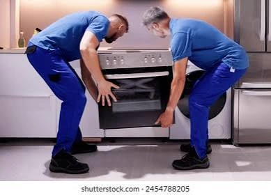 Two installers positioning a kitchen range; supplied image includes a Shutterstock credit
